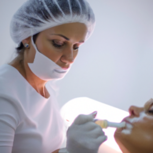 Mulher de 40 anos recebe aplicação de preenchedor facial nas maçãs do rosto por esteticista com luvas em ambiente clínico moderno e iluminado.