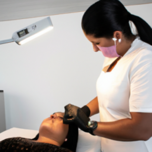 Médica aplica tratamento a laser no abdômen de uma mulher jovem com pele uniforme em clínica moderna e bem iluminada